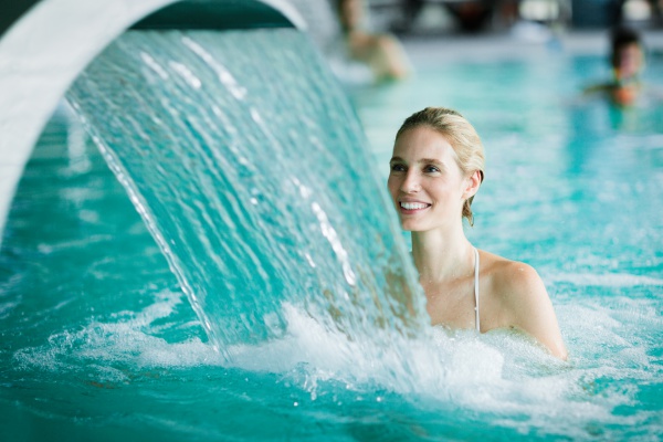 Woman enjoying hydrotherapy in spa pool Swimming pool waterfall